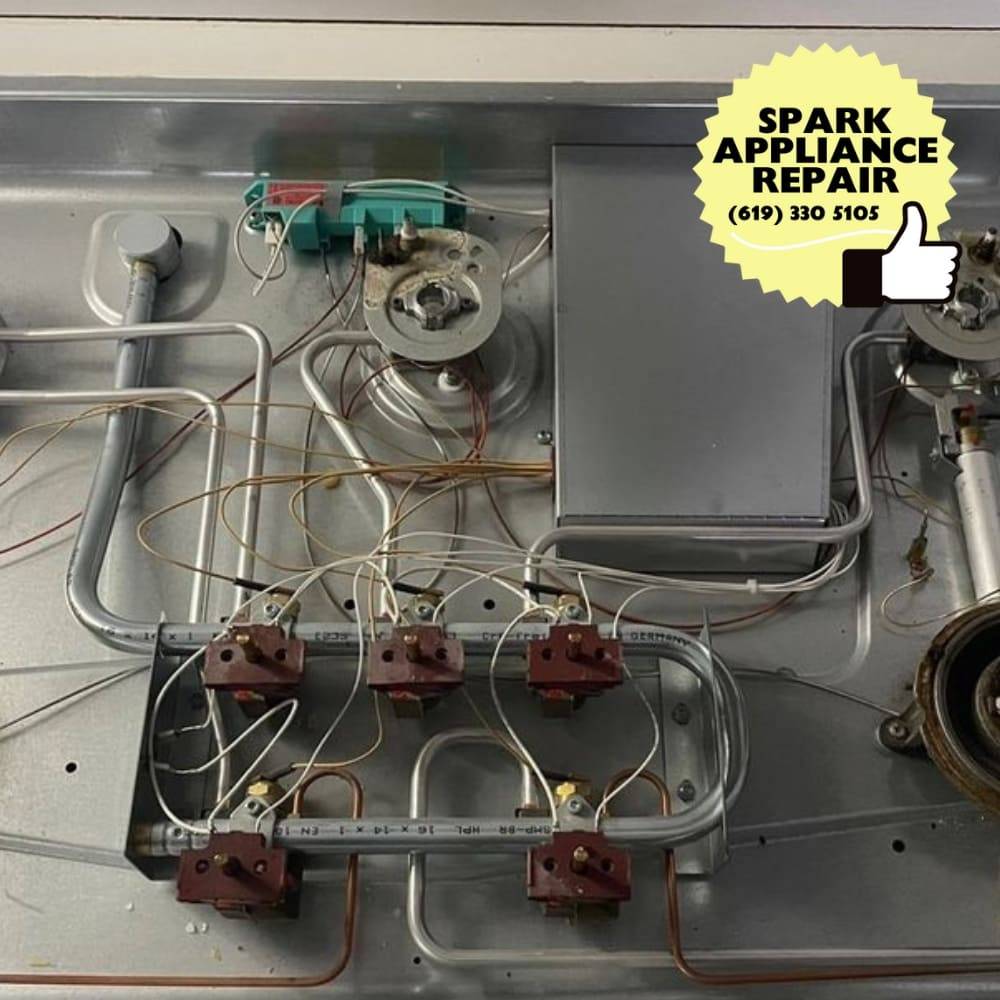 Cooktop surface internals on the bench during a San Diego service call &mdash; burner valves, wiring harness, and switches, Spark Appliance Repair