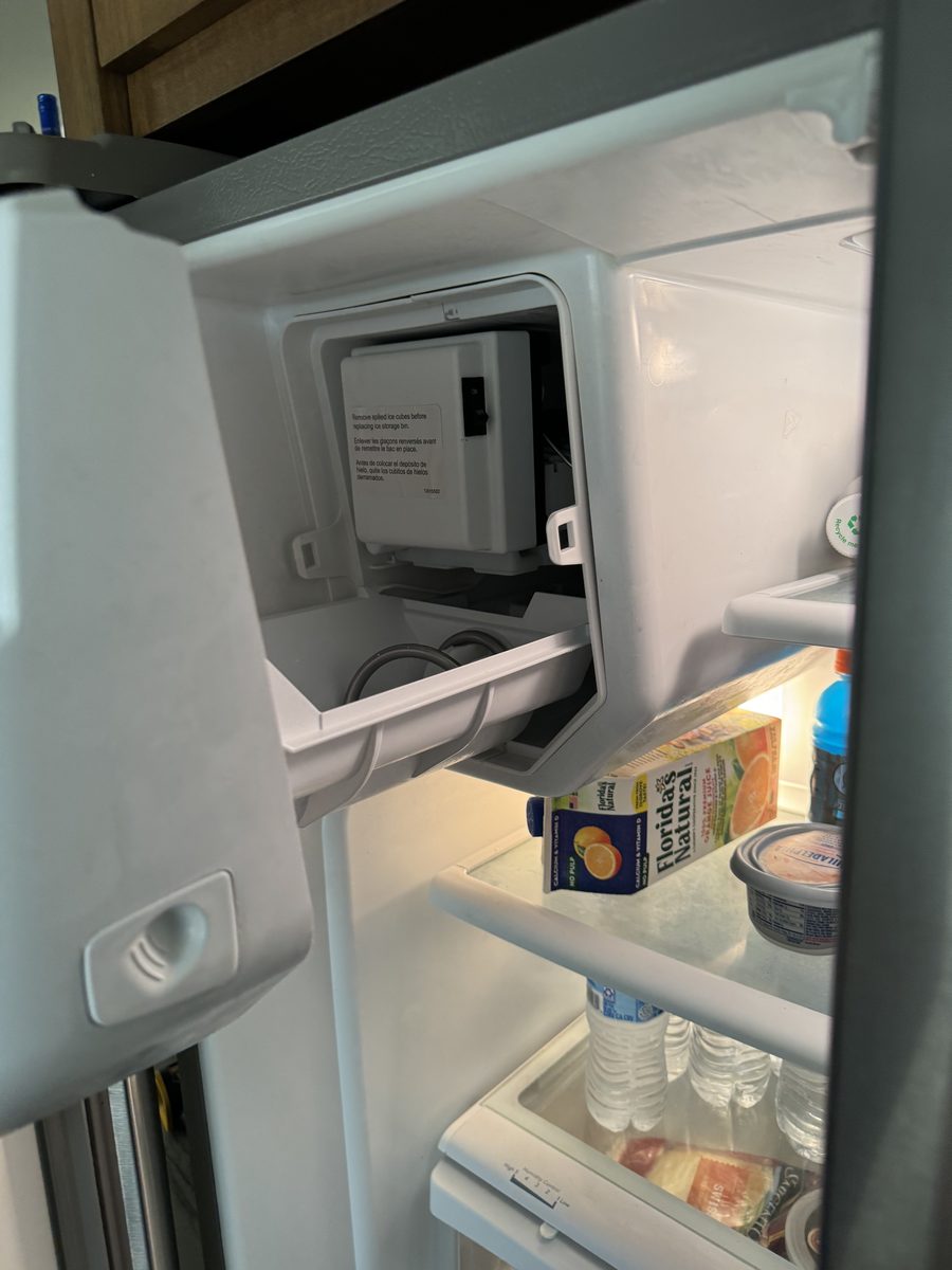 Open ice maker compartment inside a French-door refrigerator showing the ice maker's on/off switch