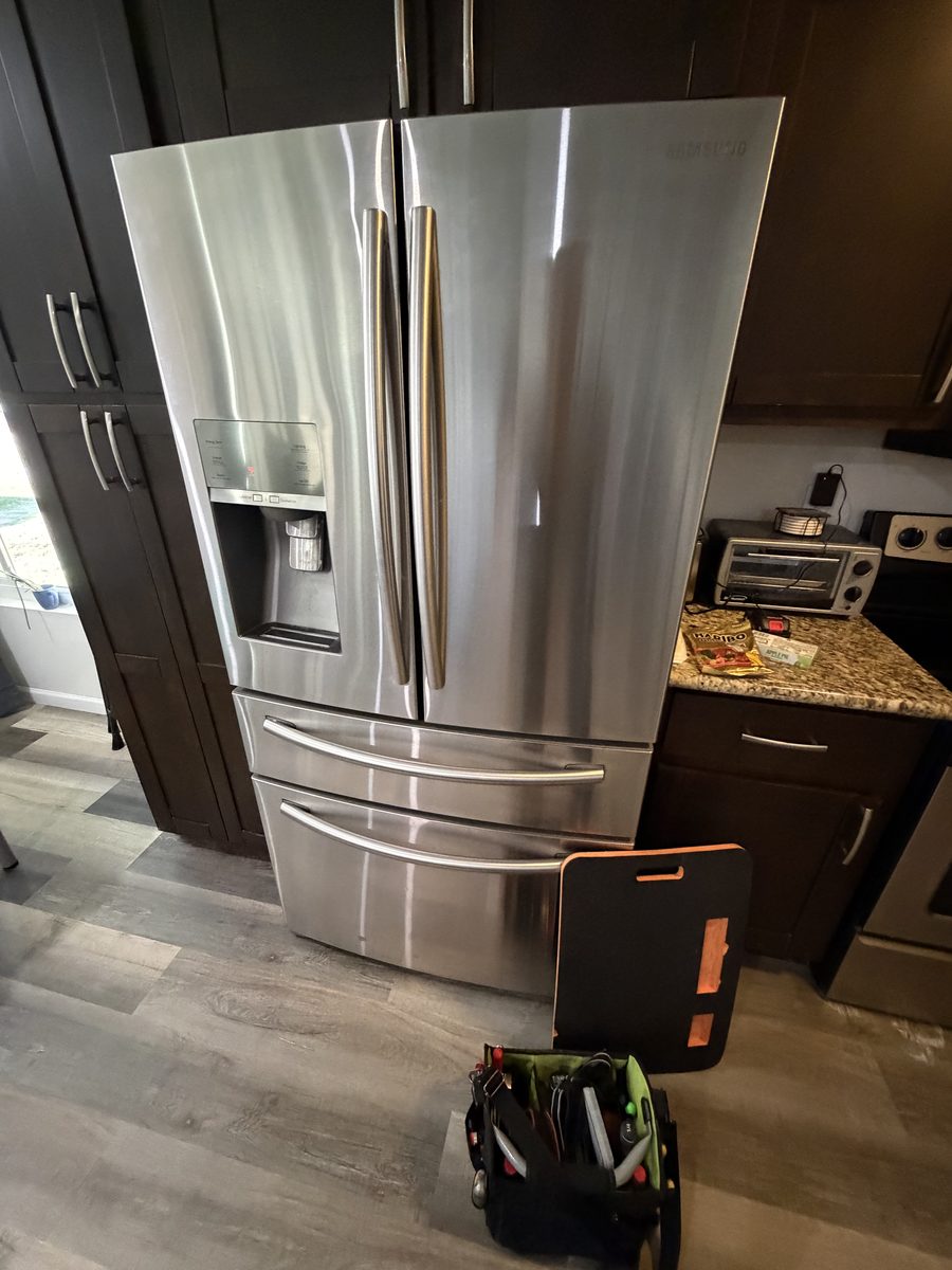 Stainless Samsung French-door refrigerator with a technician's tool bag beside it on a Spark service call in San Diego