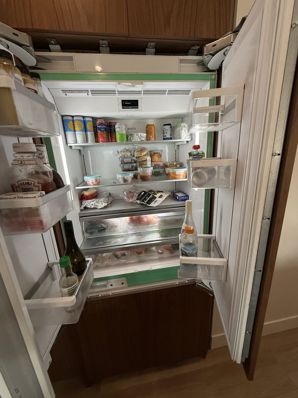Panel-ready built-in French-door refrigerator with both doors open and the shelves stocked with food