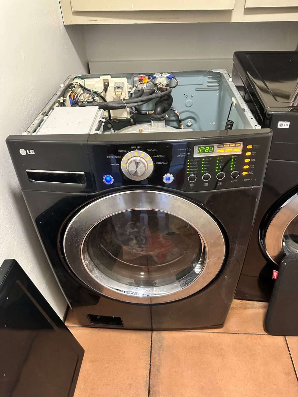 Black LG front-load washer with the top panel removed during a Spark control board and inlet valve diagnosis
