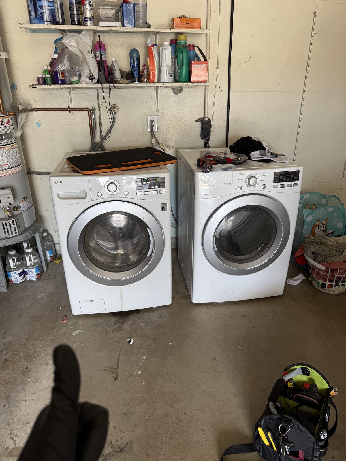 LG front-load washer and dryer pair in a Chula Vista garage with the technician tool bag on the floor