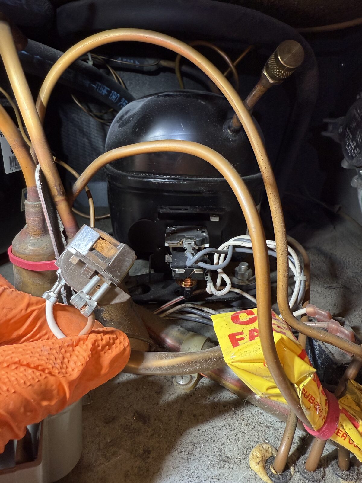 Manifold gauges connected to a refrigerator compressor during a Spark sealed-system diagnosis in Del Mar