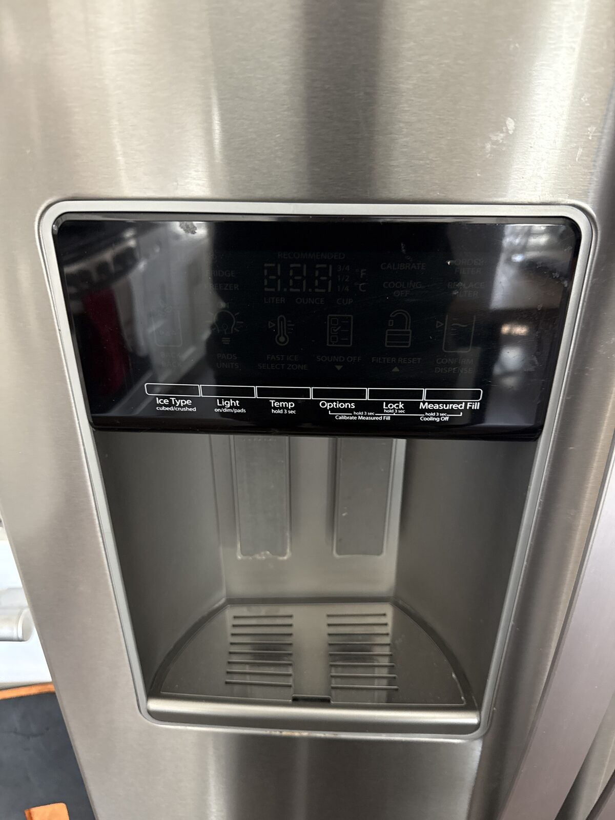 Close-up of a refrigerator door ice and water dispenser control panel with ice type, light, temperature and lock keys