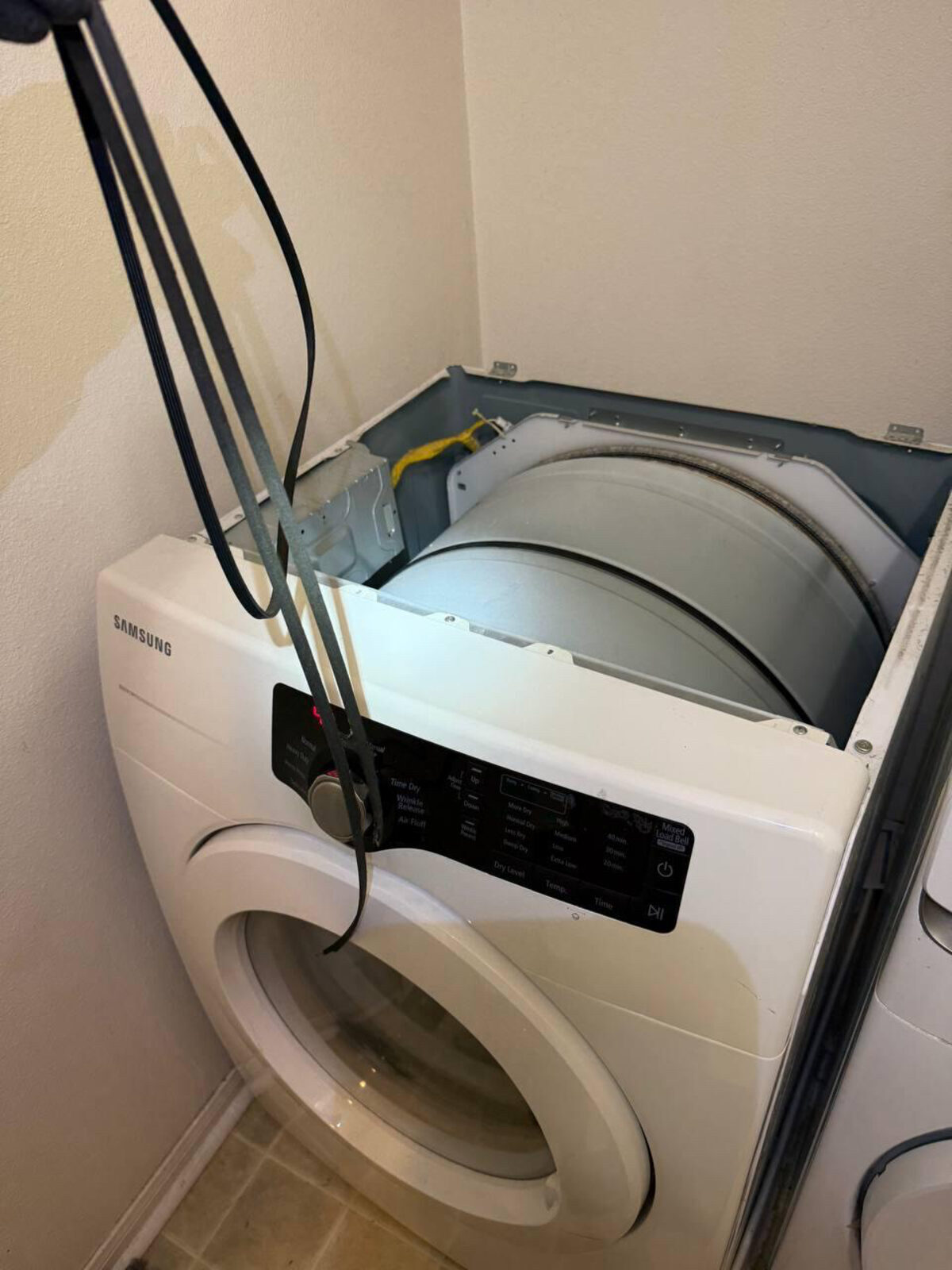 Samsung dryer with the top panel removed and the drum exposed while drum belts are held above it